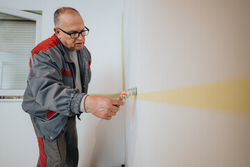 A craftsman wearing a work uniform carefully paints a wall with precision, showcasing expertise and...