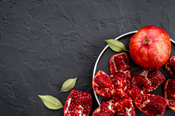 Top view of fresh ripe pomegranate and pieces on plate for eating, top view.
