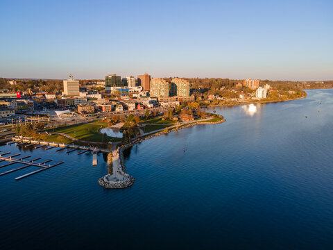 City of Barrie downtown waterfront aerial panorama drone shot. Lake Simcoe marina, condo buildings, banks, parks and infrastructure. Sunny day, blue sky.