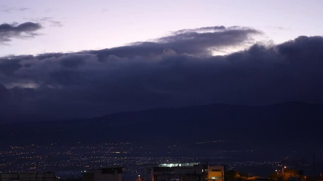 Ambato City Lights at Dawn under Moving Clouds