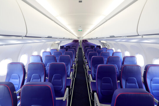 Empty interior of new modern airplane Airbus A321 XLR with blue seats and no passangers. Photographed in ambiental light. Selective focus..