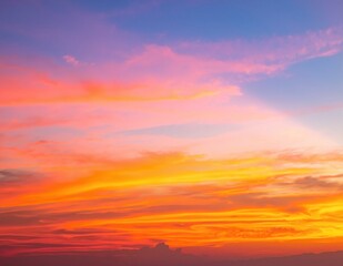 Fototapeta premium A vibrant orange sky glows at sunset, with wispy clouds catching the warm hues, creating a stunning backdrop for the tranquil landscape below.
