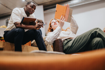 A man and a woman working together, discussing documents in an office environment. They are engaged...