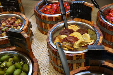 Variety of colorful pickled vegetables displayed in rustic wooden containers at a market