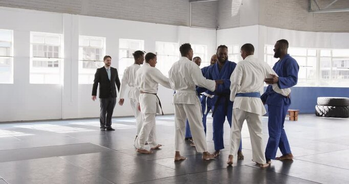 Judo practitioners in dojo gathering for training, wearing traditional uniforms