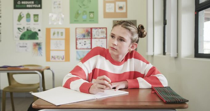 In school, young girl writing in notebook, concentrating on classroom assignment