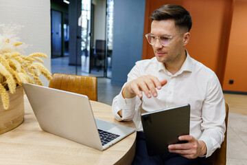 Business professional collaborates with a laptop and tablet in a modern office setting.