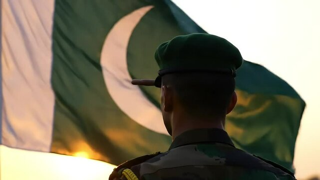 Pakistani Soldier Saluting National Flag at Sunset &ndash; Green Beret Army Officer Standing in Tribute Before Crescent Moon and Star Flag &ndash; Patriotic Military Scene