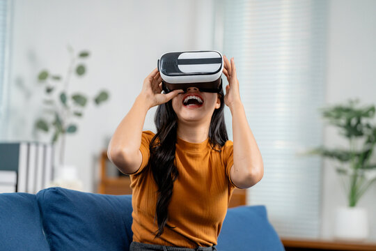 Happy young woman wearing virtual reality glasses is enjoying her experience in the metaverse
