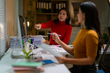 Fototapeta premium Asian businesswomen working together using computer and documents in office at night