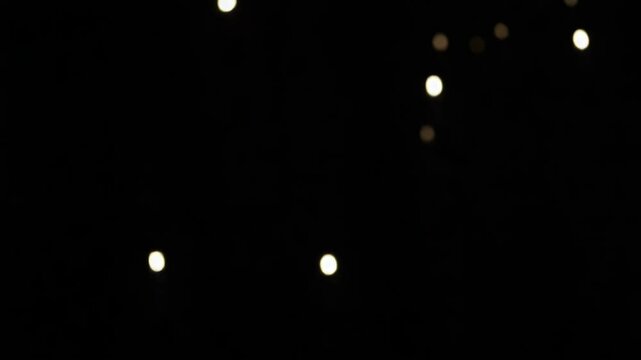 soft golden bokeh lights floating in black background, elegant blurry particles shimmer slowly, abstract romantic atmosphere