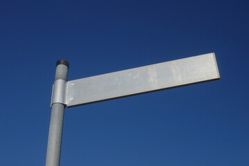 Street sign is standing on a pole in front of a blue sky