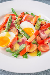 Elegant Niçoise portion with eggs, tuna, arugula, asparagus, cherry tomatoes, white plate