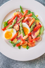 Elegant Niçoise portion with eggs, tuna, arugula, asparagus, cherry tomatoes, white plate