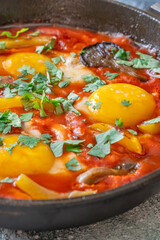 Shakshuka with mushrooms and yellow peppers topped with eggs and cilantro