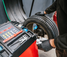 Unrecognizable mechanic preparing tire for balancing on digital wheel balancer. Car workshop concept