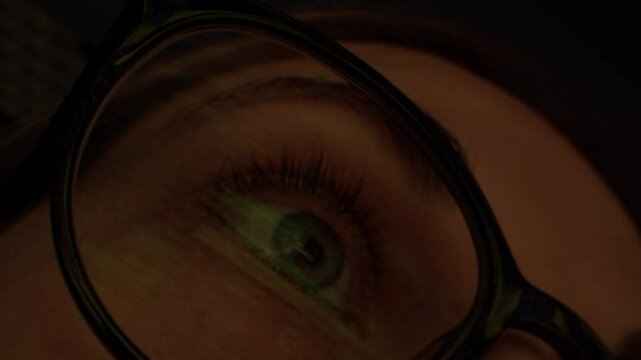 Close up of tired woman working at night on laptop, girl in eye glasses with reflections overworking busy, using computer in dark office
