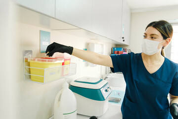 Dentist disposing medical waste into yellow safety container