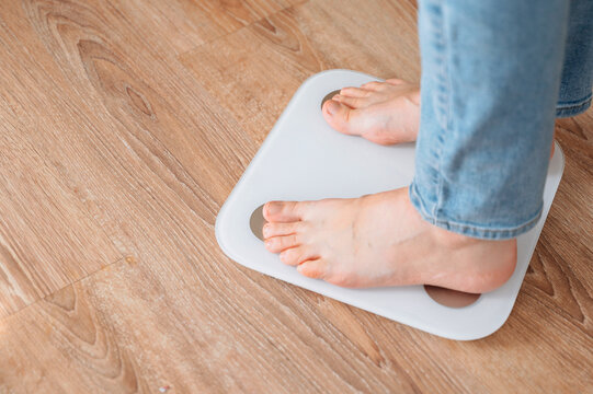 Young woman standing on scales for weight loss concept