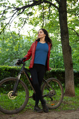 Beauty smiling woman long brown hair biking on bicycle on spring trees background and looking...