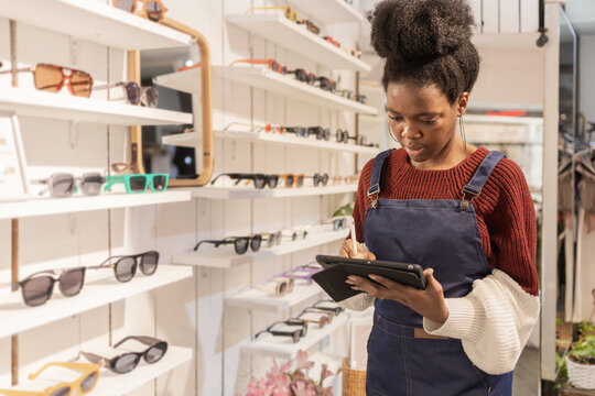 Employee Checking Inventory in a Trendy Sunglasses Store