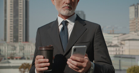 Entrepreneur scrolling social media feed on smartphone, holding coffee cup, modern business...