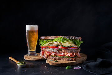 Layered sandwich and beer pairing on rustic wooden board