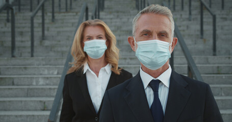 Serious businesspeople in face masks looking at camera, commitment to crisis response