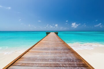 Fototapeta premium Wooden Pier Leading to Turquoise Ocean Under a Bright Blue Sky on a Tropical Beach