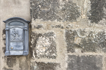 vintage mailbox with relief of postman on bicycle on facade of old stone house with empty space. mail delivery concept