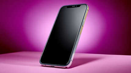 Phone is laying on a pink surface. The phone is black and silver. The pink background gives the image a soft and calming mood