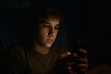 Teenage Boy Using Smartphone in Bed at Night &mdash; Realistic Low Light Scene