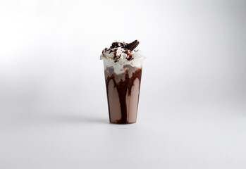 Milkshake with syrup, whipped cream and cookies in a glass. on a white background.