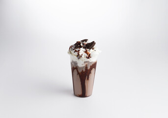 Milkshake with syrup, whipped cream and cookies in a glass. on a white background.