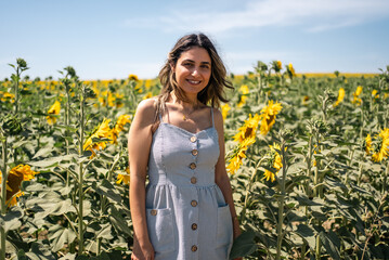 Happy woman arms raised and enjoying in sunflower field.