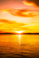 Fototapeta premium Sunset on the beach with the silhouette of mountains and fishermen with their boats at sea