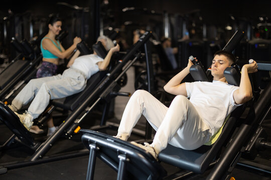 Active and mobile lifestyle, sports as hobby and way of life. Guy sports club visitor exercises on hack squat machine. Client performs exercises, combines dynamic and static loads on body.