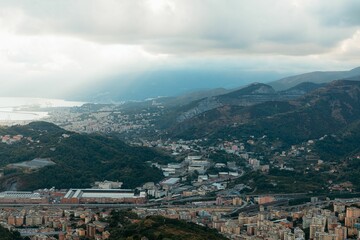 Obraz premium Genoa cityscape with mountains and clouds.