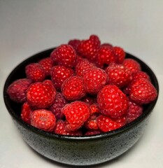 Fresh juicy raspberries. raspberries in a black bowl on a white background
