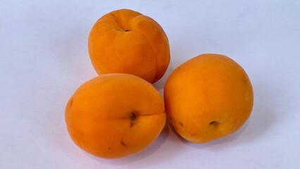 Three ripe, orange apricots on a white background.
