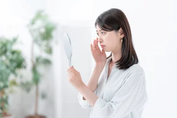 Fotobehang 手鏡を見て悩む女性 © naka