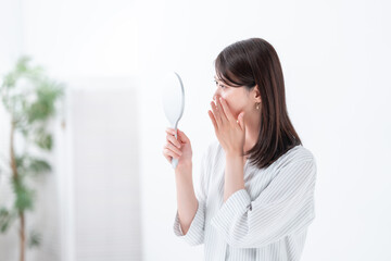 手鏡を見て悩む女性