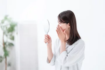 Fotobehang 手鏡を見て悩む女性 © naka