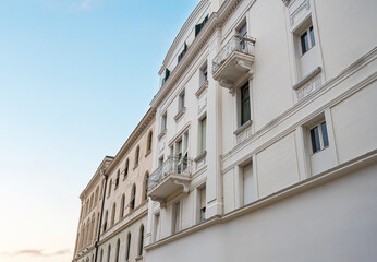 A row of elegant, historic European buildings with ornate balconies and window shutters under a clear blue sky.