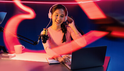 Smiling creative young beautiful Asian influencer talking in channel with positive podcast speech...