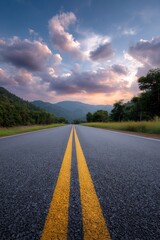 Paved road stretches toward distant mountains beneath a sky filled with dramatic clouds