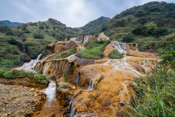 High-resolution image of the Golden Waterfalls in northern Taiwan, a spectacular cascade tinted by mineral-rich waters flowing over rust-colored rocks near Jinguashi