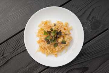 Sauerkraut topped with green sprouts on a white plate