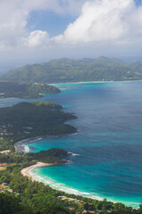 The view on the coastline with beaches and green hills, islands and blue Indian Ocean from the top of the mountain Morne. Mahe, the Seychelles
