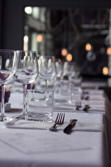 Fine dining restaurant table set with sparkling wine glasses, old fashioned glasses, and pristine white napkins, viewed from low angle creating an elegant perspective.